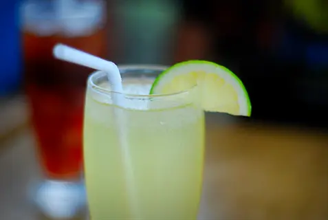 calamansi juice glass with straw and lime wedge on the rim
