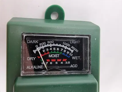 close-up dial of a soil ph probe meter showing light, moisture, and acidity scales