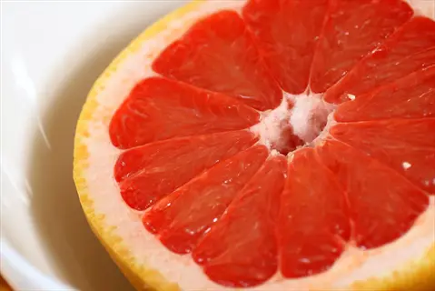 close-up of a halved ruby red grapefruit on a white plate