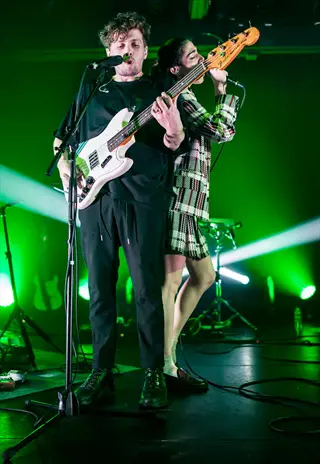 echo duo performing live onstage with bass guitar and green lighting