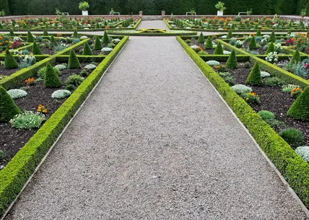 formal garden with gravel path and succulent pathway border edging, flowers and topiary hedges