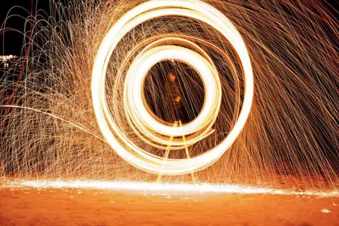 pyromania fire spinning creates bright circular sparks at night