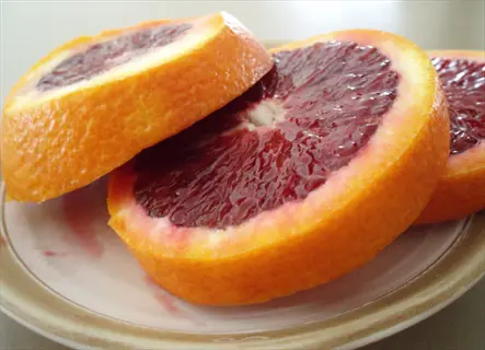 sliced budd blood orange rounds on a plate with deep red flesh and orange rind