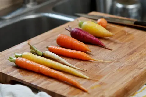 winter carrots harvest arranged on a wooden cutting board near a kitchen sink